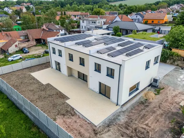 Letecký pohled na trojdům s fotovoltaikou a krajinou v pozadí