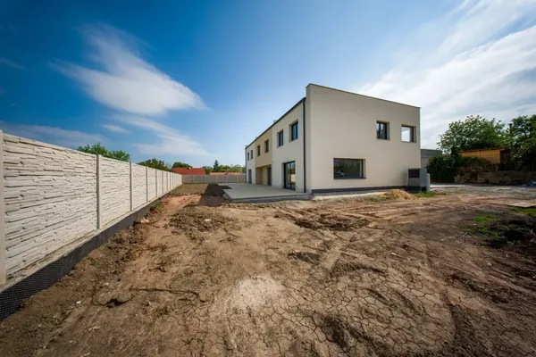 Zadní pohled na trojdům s terasou a zahradou